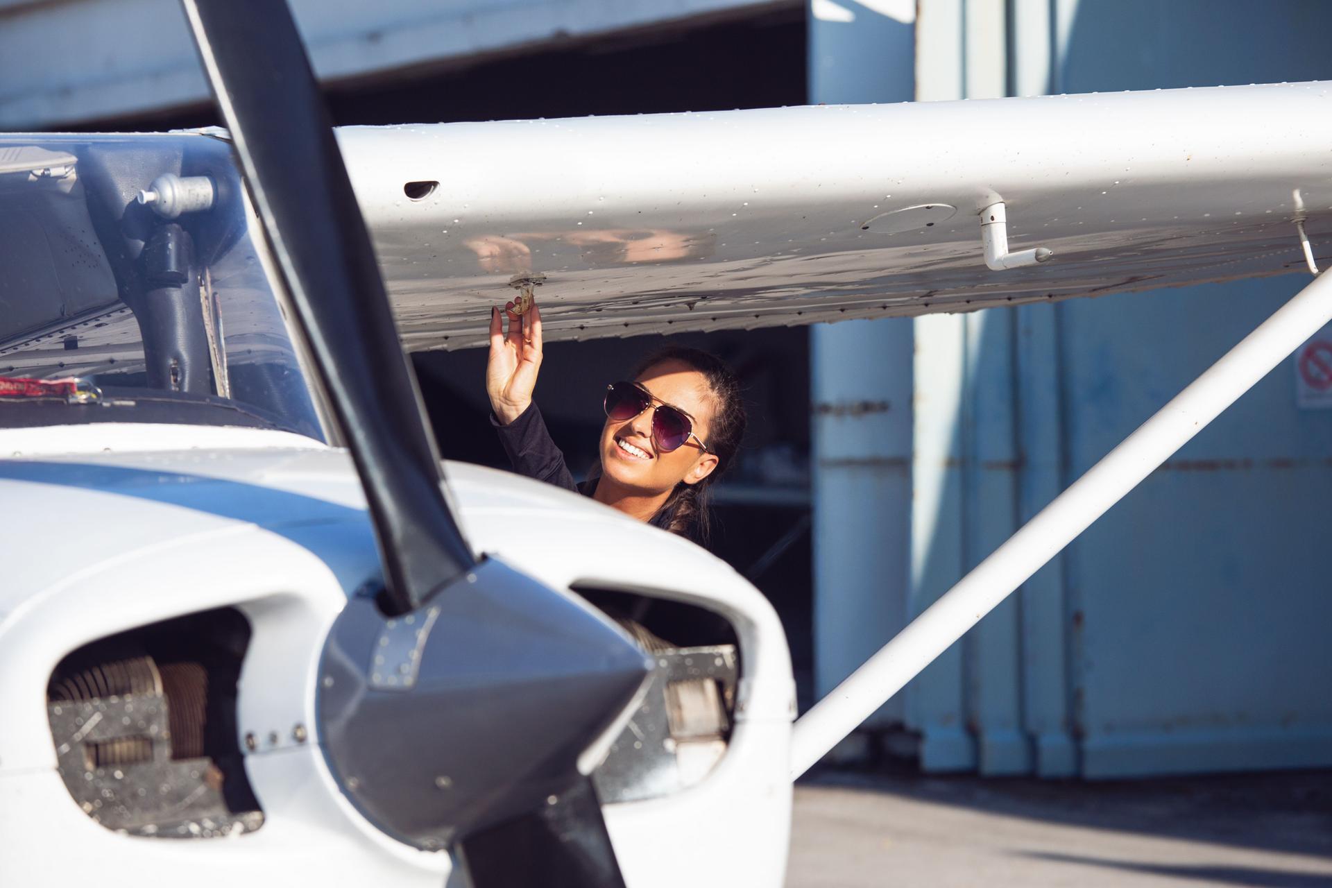 Female pilot in sunglasses with modern small aircraft in background